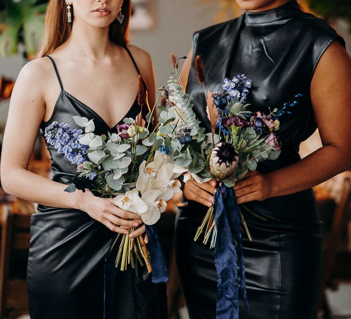 Bridesmaids in leather dresses holding moody dark wedding flowers 