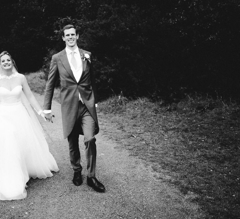 Bride & groom walk outdoors in black & white image