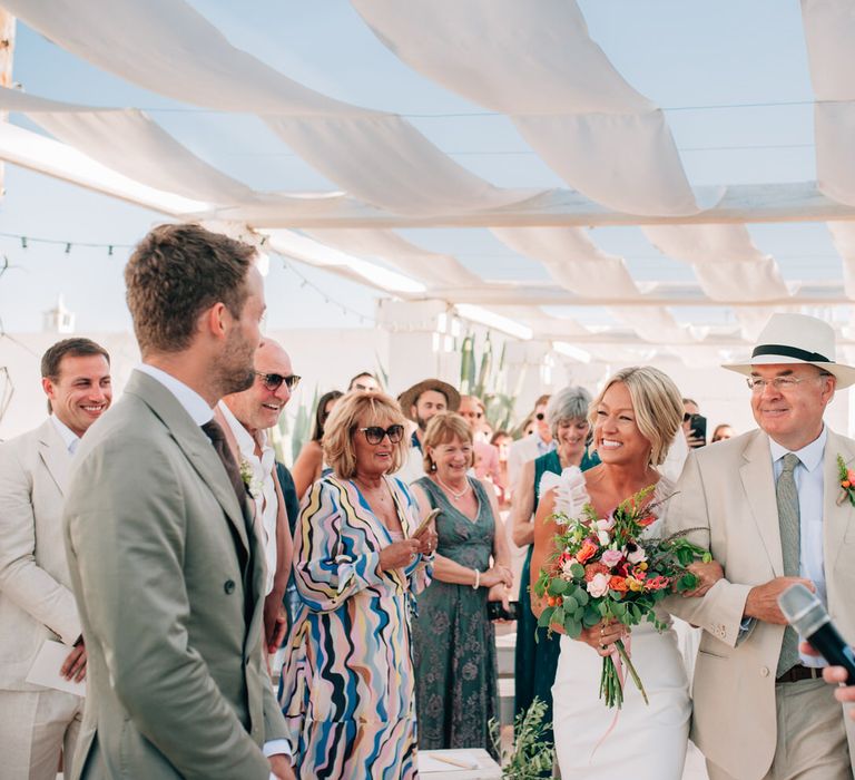 The bride arriving at the altar with a huge grin on her face, smiling at the groom