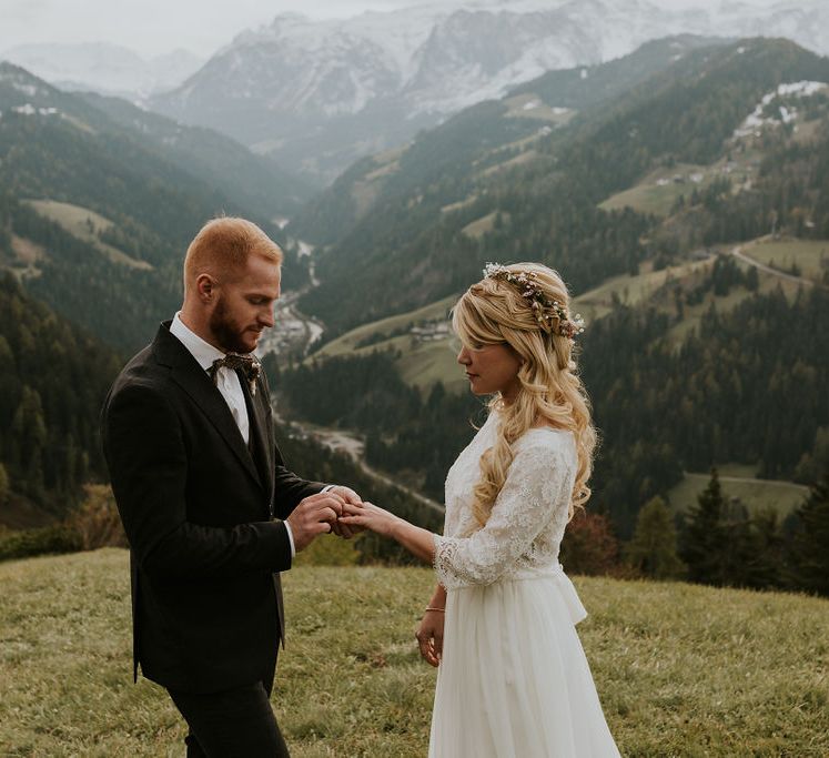 Groom in a dark check suit putting the wedding ring on his brides finger at their intimate elopement 