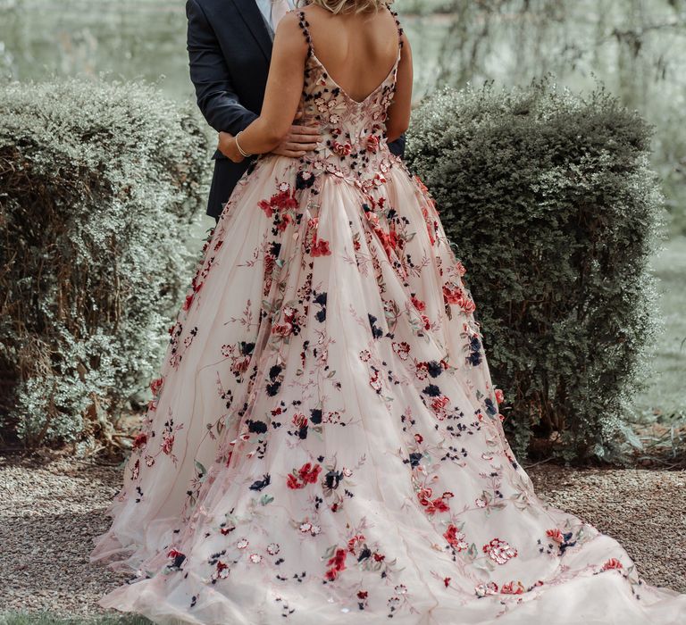 Bride & groom stand together outside surrounded by green foliage