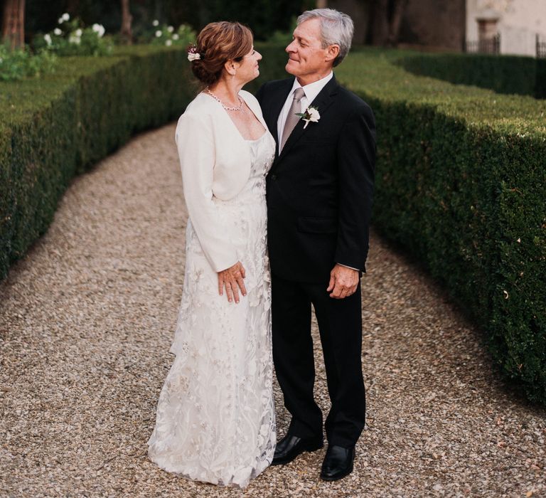 Bride & groom stand within Villa gardens whilst looking lovingly at one another on their wedding day