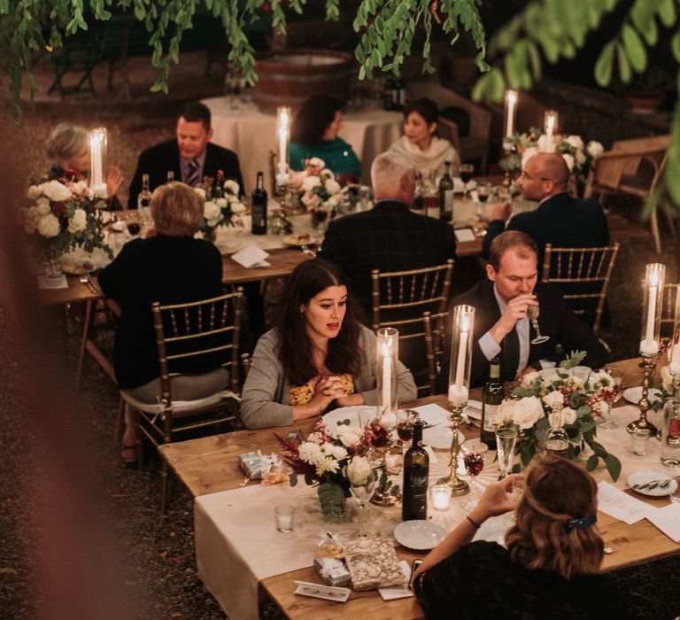 Wedding guests during outdoor wedding reception dinner with rustic Italian vibe and twinkling fairy lights