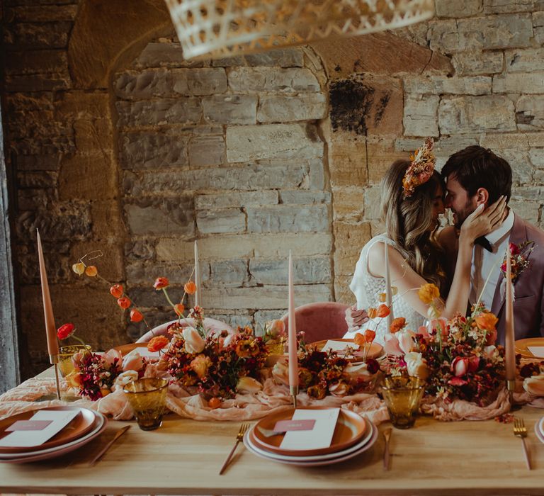 Bride and groom at romantic wedding table lined with orange and blush flowers