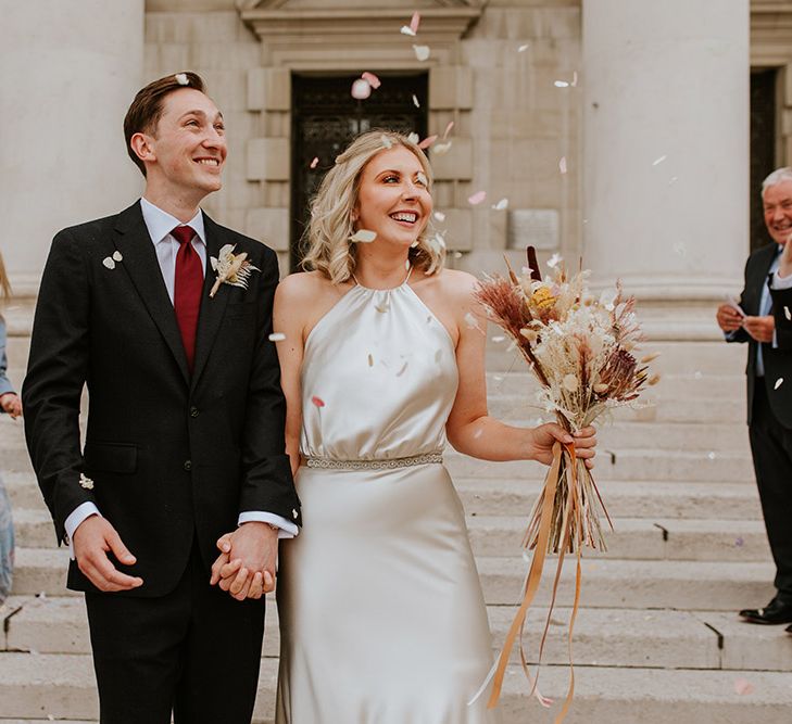 Confetti moment outside Leeds Civic Hall with groom in a black suit and bride in a Kate Beaumont champagne colour wedding dress