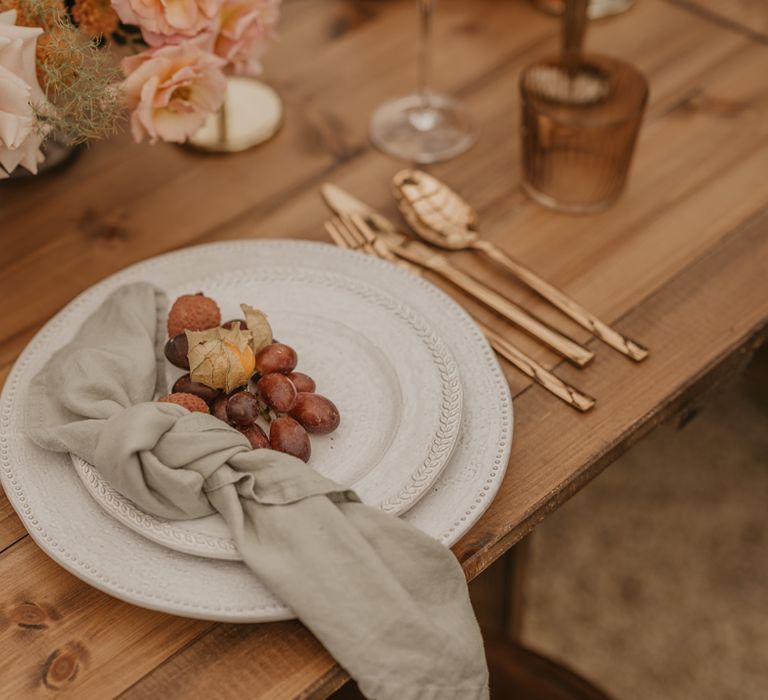 Place setting with ornate table ware, gold cutlery and fruit decor