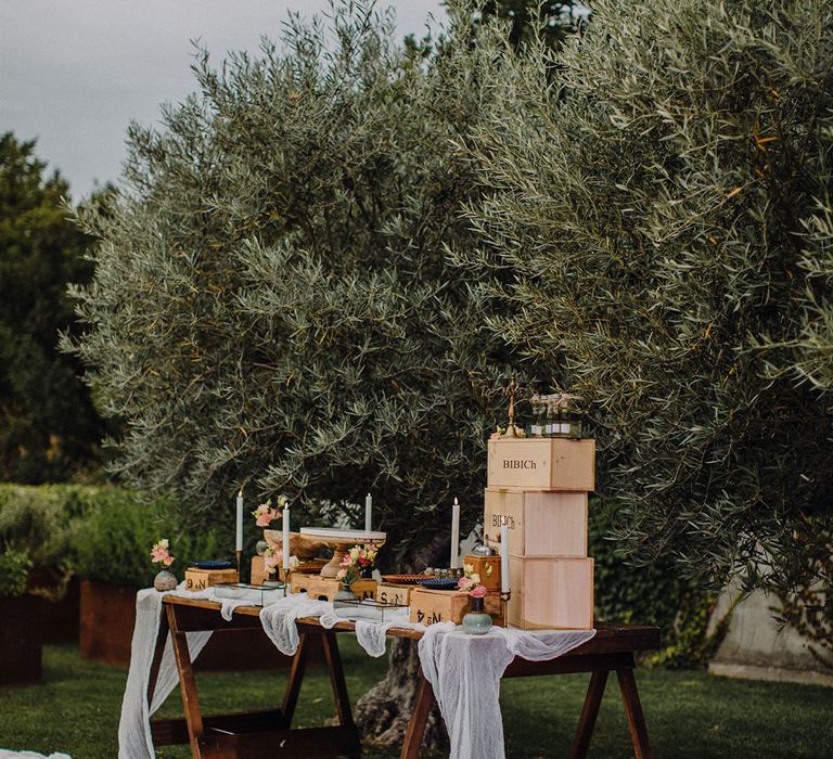 Rustic dessert table setting complete with gossamer fabric running across the table