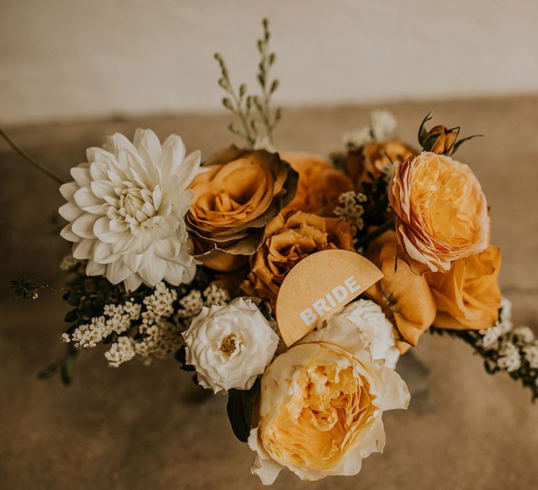 Orange and cream wedding flowers with a bride table name place card 