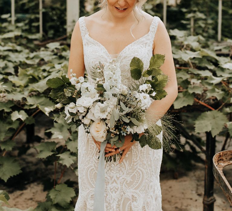 Bride clutches large white flower and foliage wedding bouquet