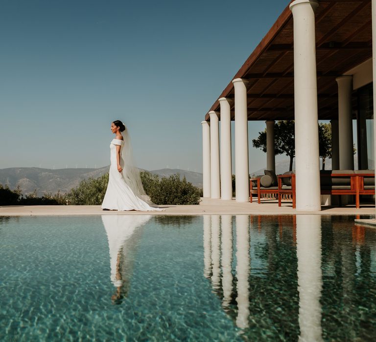 Bride walks in front of pool as her dress flows behind her | Hannah MacGregor Photo & Film