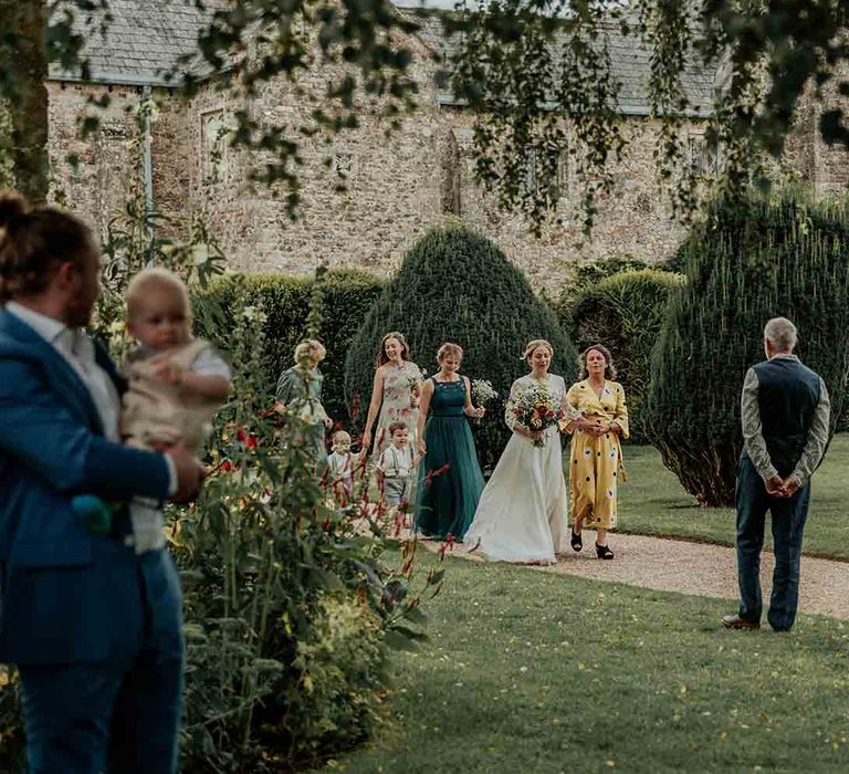 Bride makes her way to outdoor ceremony with bridesmaids