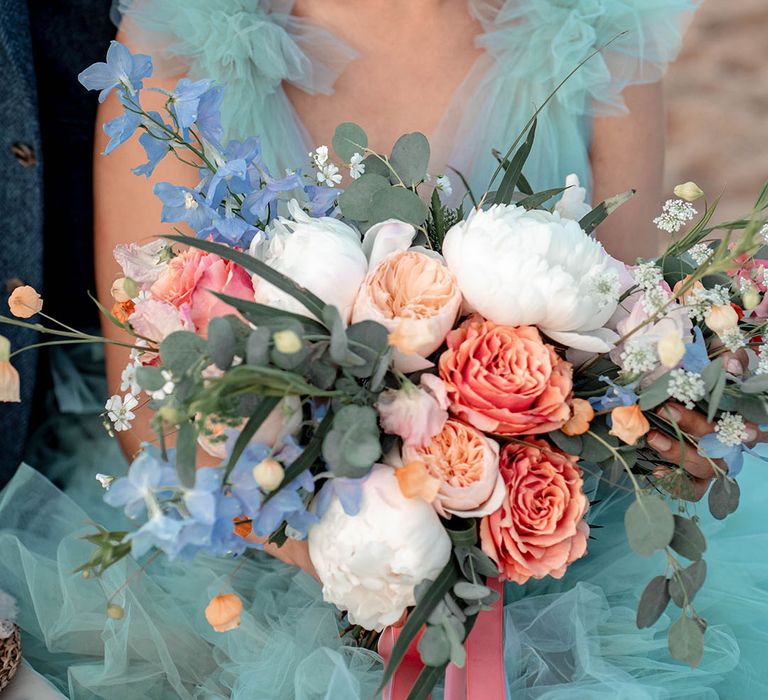 Pastel wedding bouquet with green foliage, white peonies, peach David Austin roses and blue forget me nots 