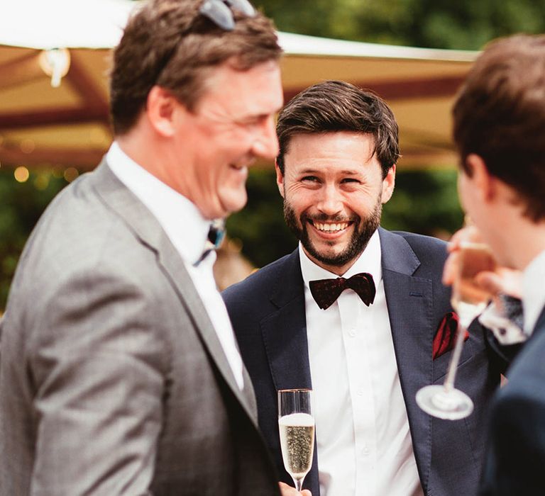 Groom laughs with his groomsmen on wedding day