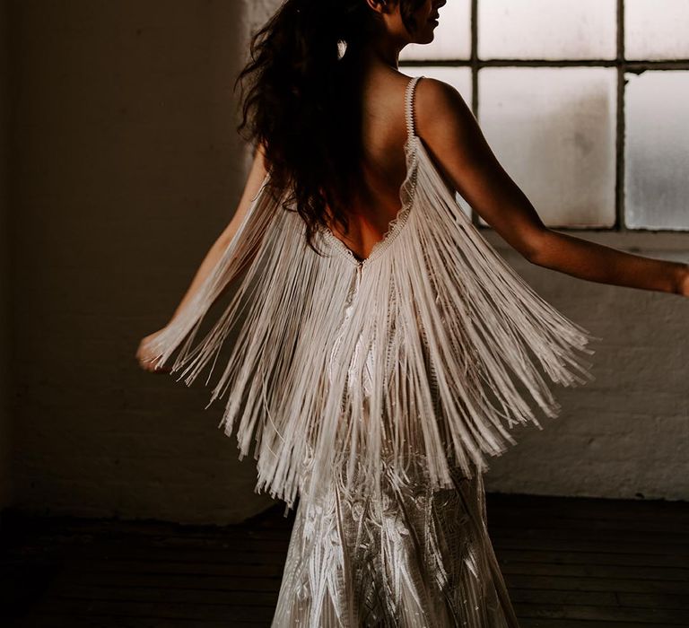 Boho bride with messy ponytail twirling in a Shikoba Bride wedding dress with low back a tassel detail 