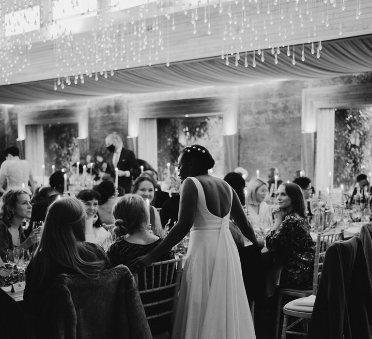 Black bride with peal hair pins talking to her guests during the wedding reception 