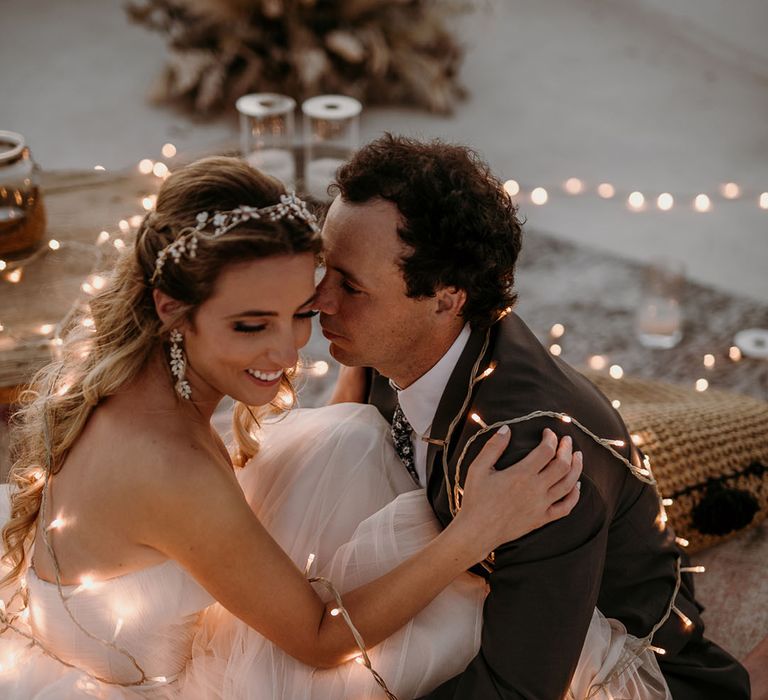 Bride & groom have string of fairy lights around them outdoors on their wedding day