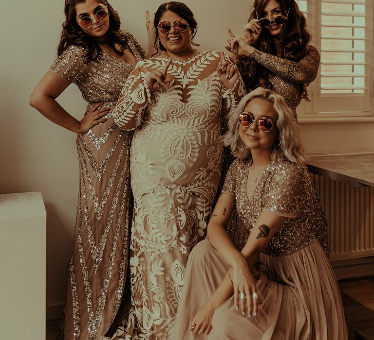 Stylish bridal party standing under a neon sign with bride in a Rue de Seine wedding dress and bridesmaids in sequin dresses 