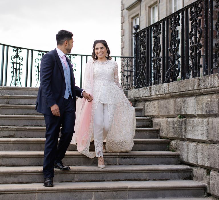 Bride & groom walk with one another holding hands on their wedding day