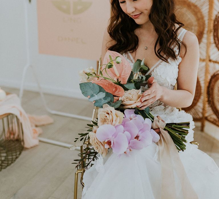 Bride holds Bouquet of handpicked flowers filled with different tones of peaches, pinks & greens