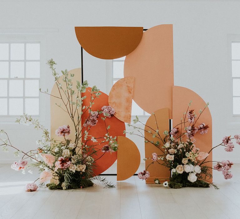 Asian wedding decor with geometric shape backdrop, paper lanterns and long steam flower arrangement 