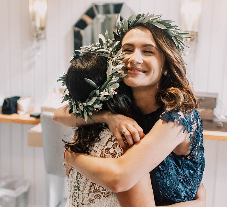 Bride hugs wedding guest who wears green lace gown