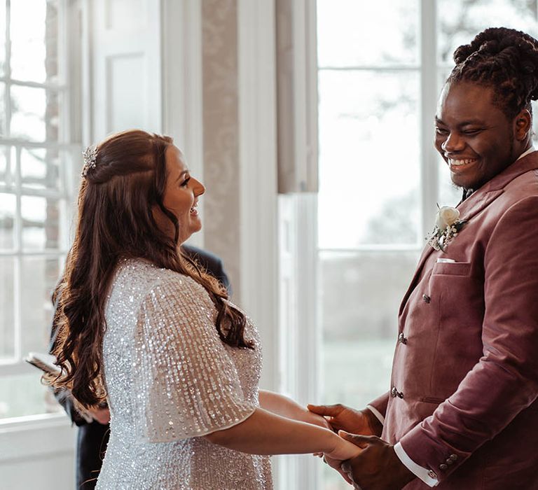 Bride & groom hold hands and look lovingly at one another on their wedding day