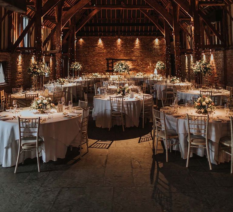 Wedding venue at Cooling Castle Barn with golden and white tables and white and orange flower decorations 