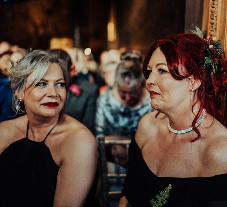 Bridesmaids in black dresses and matching bright and colourful flower hair accessories 