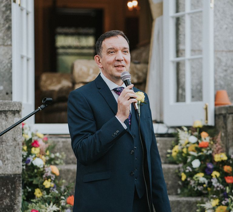 Guest in pink flower tie reads out his speech to the wedding party for LGBTQI+ country house wedding