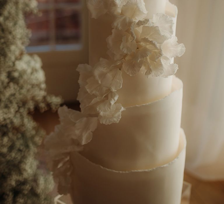 white cascading flower detail on white wedding cake 