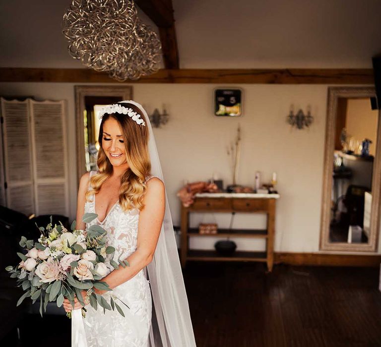 Bride in white flower headband with lace wedding dress with sheer train and long veil holding pink and white wedding bouquet