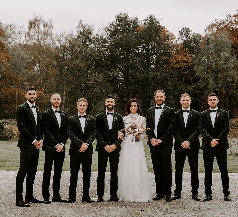 Bride and groom with groomsmen in black velvet outfits for winter wedding