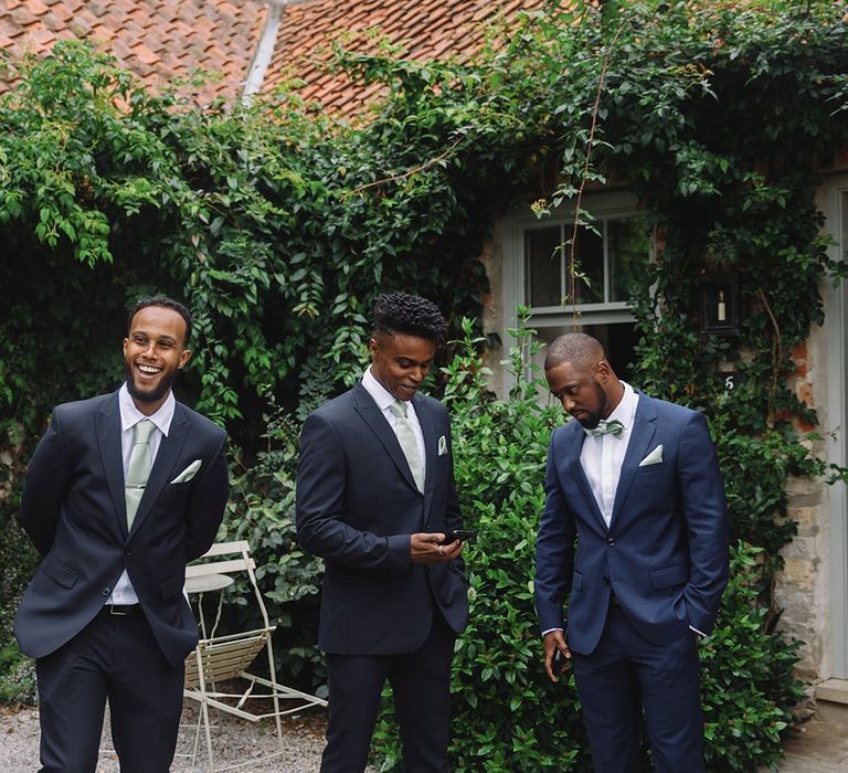 Groomsmen in matching dark suits with mint green tie and handkerchief with groom in matching mint green bow tie and blue suit 