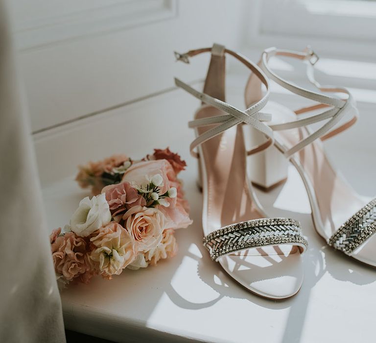 White wedding shoes with sparkly encrusted strap with pink and white flowers on flower crown