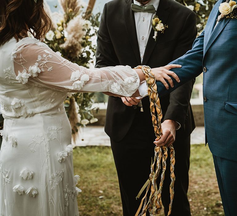 hand fasting ceremony at destination wedding with bride in a long sleeve appliqué wedding dress