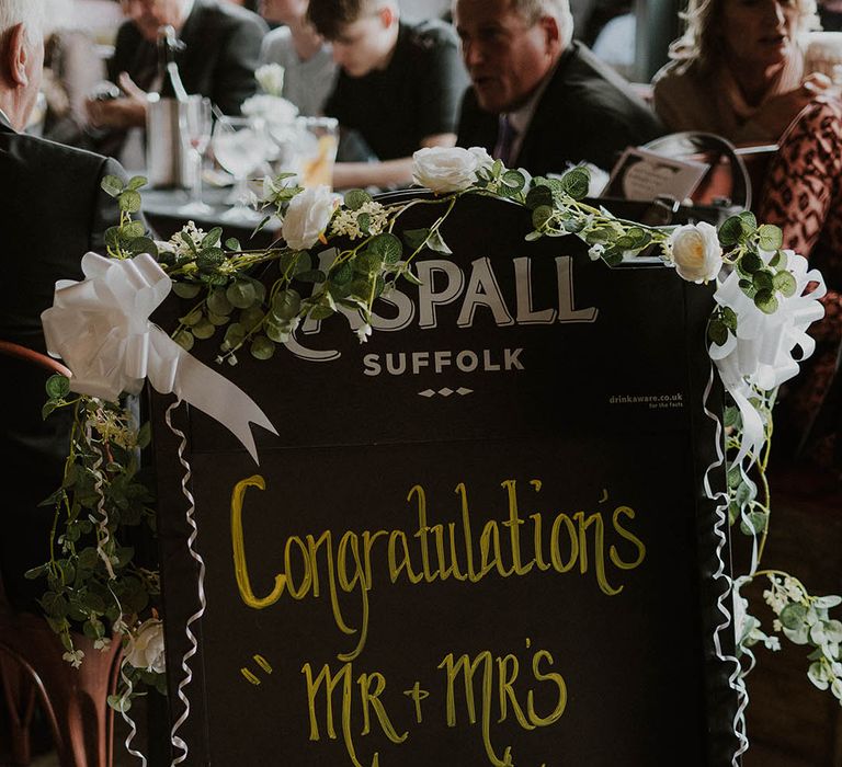 Chalk board pub welcome wedding sign with flower decor 