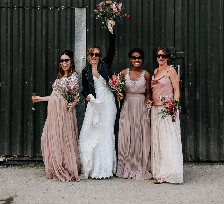 Bride and bridesmaids in pink dresses and leather jackets wearing sunglasses 