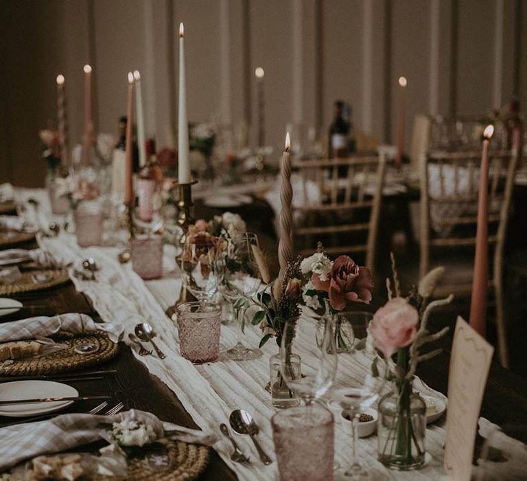 Soft and romantic wedding tablescape with muted pink, white and neutral candles, white table runner and roses