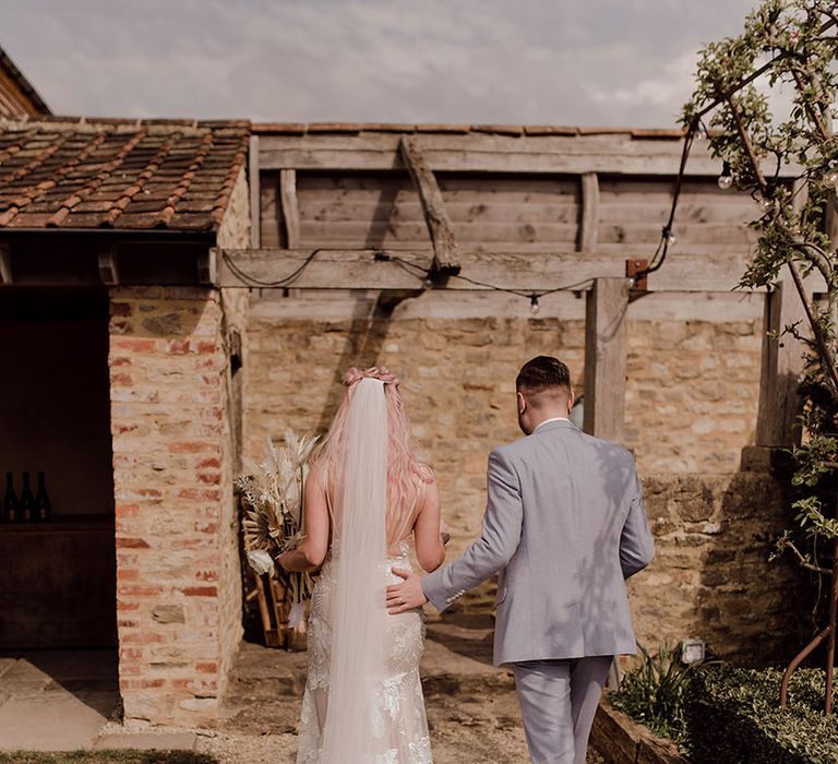 Bride wearing dramatic floor-length veil walks with her groom outdoors after wedding ceremony