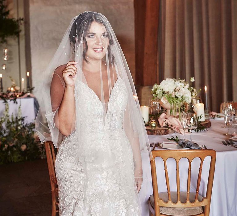 Bride in a fitted lace wedding dress with fishtail and pearl encrusted wedding veil 