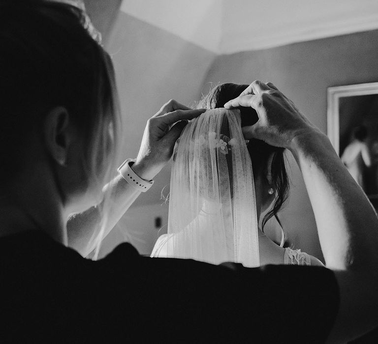 Bride has veil placed in low curled bun complete with floral hair accessories 