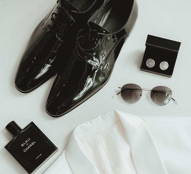 Grooms white suit jacket beside wedding shoes and cufflinks before wedding ceremony 