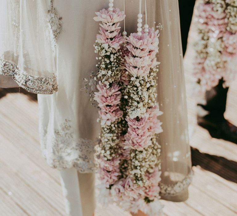 Wedding guest holds pastel coloured lei complete with pearls and white ribbon