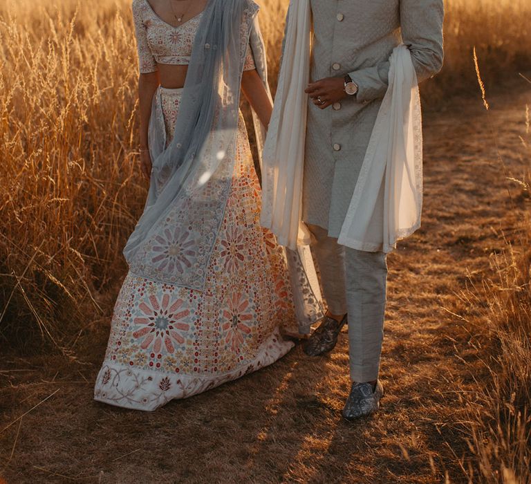 Bride & groom walk through fields during golden hour at High Billinghurst Farm 