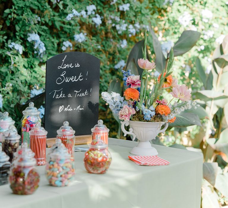 Colourful sweet station complete with chalkboard and colourful floral arrangement 