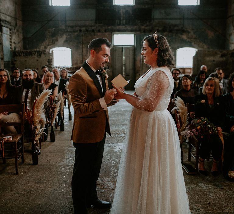 Bride and Groom exchange rings at alter in front of pampas grass lined aisle