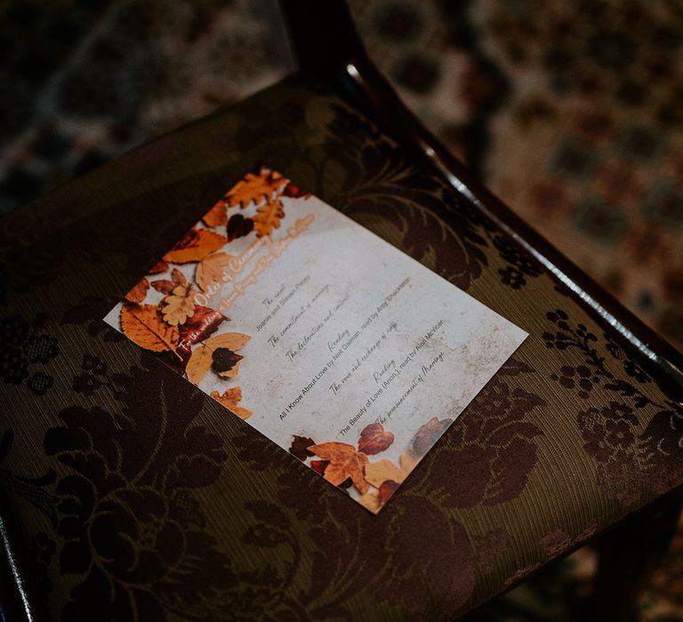 Autumnal themed wedding order of ceremony stationery with orange, yellow and brown leaf decorations