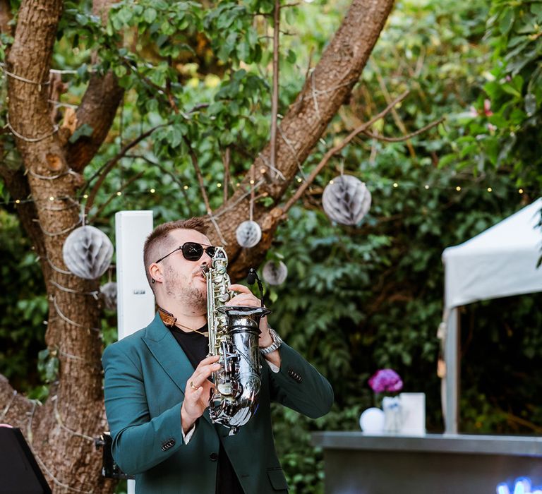 Saxophonist plays outdoors during wedding reception 