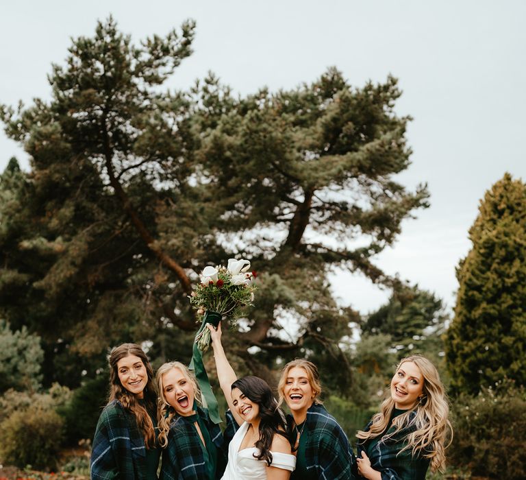 Bridesmaids in green bridesmaid jumpsuits complete with tartan shawl coverups 