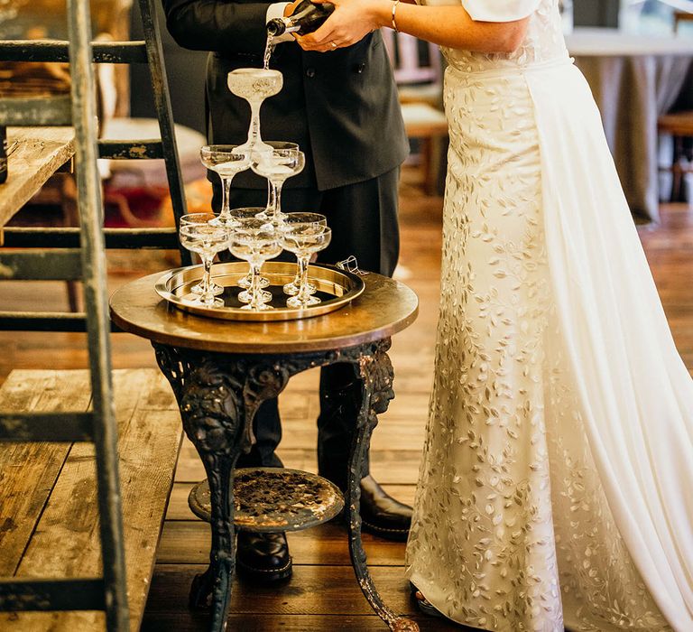 Bride & groom pour champagne into champagne tower